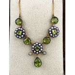 A yellow and white metal centrepiece necklace having floral cluster designs set with peridot,