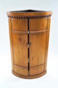A 19th century pine corner cupboard, with dentil cornice above two rounded doors,