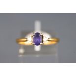 A yellow and white metal three stone ring set with an oval faceted cut tanzanite