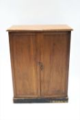 A mahogany side cabinet of plain rectangular form with two panelled doors, raised on a plinth base,