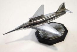 An Art Deco style table lighter in the form of a chrome jet plane, on ebonised base,