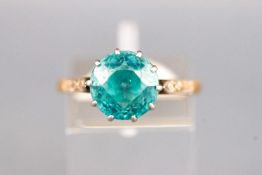 A yellow and white metal dress ring set with a round faceted cut blue zircon