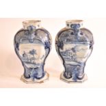 A pair of 19th century Delft baluster vases, each painted with a house in a landscape, marked,