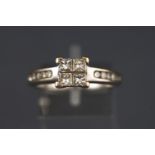 A white metal dress ring set with four princess cut diamonds