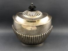 A silver tea caddy of semi fluted oval form, the hinged domed lid with an ebony finial,