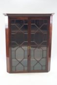 A 19th century mahogany hanging corner cabinet, with dentil cornice and two astral glazed doors,
