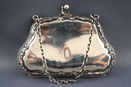 A small silver purse of traditional shape form on a chain