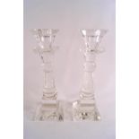 A pair of glass candlesticks of multi facet cut baluster form raised on square feet.