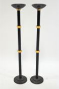 A pair of black and gilt decorated floor standing candlesticks with wine bowl sconces