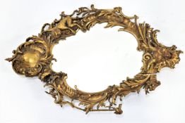 An unusual eighteenth century and later cartouche shaped wall mirror the framed carved and gilded