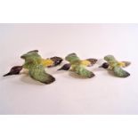 A group of three graduated Beswick green woodpeckers in flight,