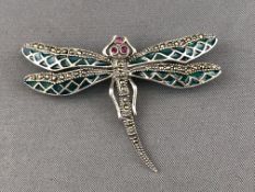 A white metal dragon fly brooch.