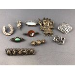 A collection of ten white metal brooches of various designs,