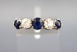 A yellow and white metal half hoop ring set with three round faceted cut sapphires