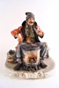 A Capodimonte figure 'Chestnut roaster', showing an old man in a red coat sitting at a brazier,