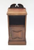 A 19th century mahogany pot cupboard, with shaped back above an open shelf above a panelled door,