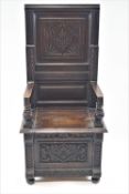 A 17th century style oak hall chair with carved panelled back,