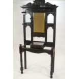 A Victorian carved oak hall stand with mirror above a hinged box on turned legs,