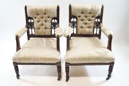 A pair of Victorian mahogany and button back armchairs with turned legs on casters, 86cm high,