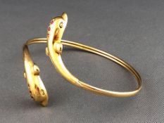 A yellow metal crossover double dolphin bangle each set with three commercial quality 1.40mm rubies.