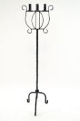 A wrought iron tripartite floor standing torchere, designed in the the form of a lyre,