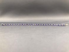 A white metal line bracelet set with oval faceted tanzanite