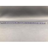 A white metal line bracelet set with oval faceted tanzanite