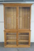 A large 19th century pine display cabinet with two glazed doors above a further two glazed doors,