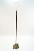 A brass standard lamp with fluted column on round base on three paw feet,