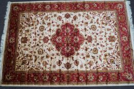 A machine woven Keishan style rug with central medallion issuing scrolling flowers on a beige ground