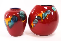 Two Poole pottery vases, both decorated in blue, green and yellow, on a red ground,