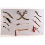 A specimen board of miniature swords and other items 40cm x 65cm