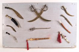 A specimen board of miniature swords and other items 40cm x 65cm