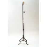 A wrought iron adjustable standard lamp on three scroll legs,