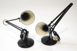 Two black anglepoise lamps with round bases,