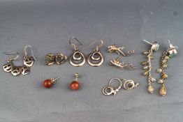 A collection of seven pairs of white metal earrings of variable designs.