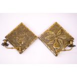 A pair of Arts and Crafts brass wall sconces each decorated with a vase of flowers and a brass