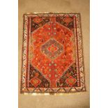 A rug with central flowerhead medallion on a flower filled red ground within one border,