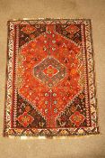 A rug with central flowerhead medallion on a flower filled red ground within one border,