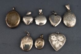 A collection of eight white metal locket pendants of variable size and shape.