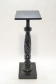 An ebonised torchere,