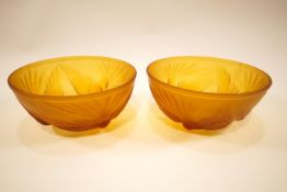 A pair of matt finished Art Deco pressed amber glass bowls, decorated with birds in flight,