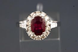 A white metal cluster ring set with an oval faceted cut treated ruby