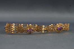 A yellow metal gate link bracelet set with three oval faceted cut amethysts.