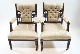 A pair of Victorian mahogany and button back armchairs with turned legs on casters,