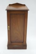 A 19th century mahogany pot cupboard, with raised back above a panelled door on plinth base,