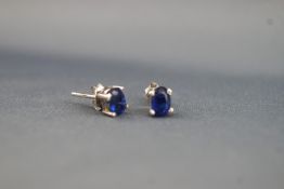 A white metal pair of single stone stud earrings. Each set with an oval faceted cut Kyanite.