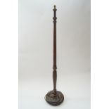 An oak standard lamp with turned tapering form on a round base and turned feet,