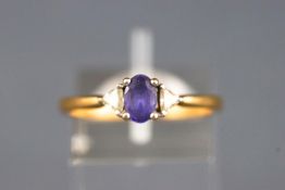 A yellow and white metal three stone ring set with an oval faceted cut tanzanite