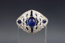 A white metal dress ring set with a central cabochon blue sapphire.
